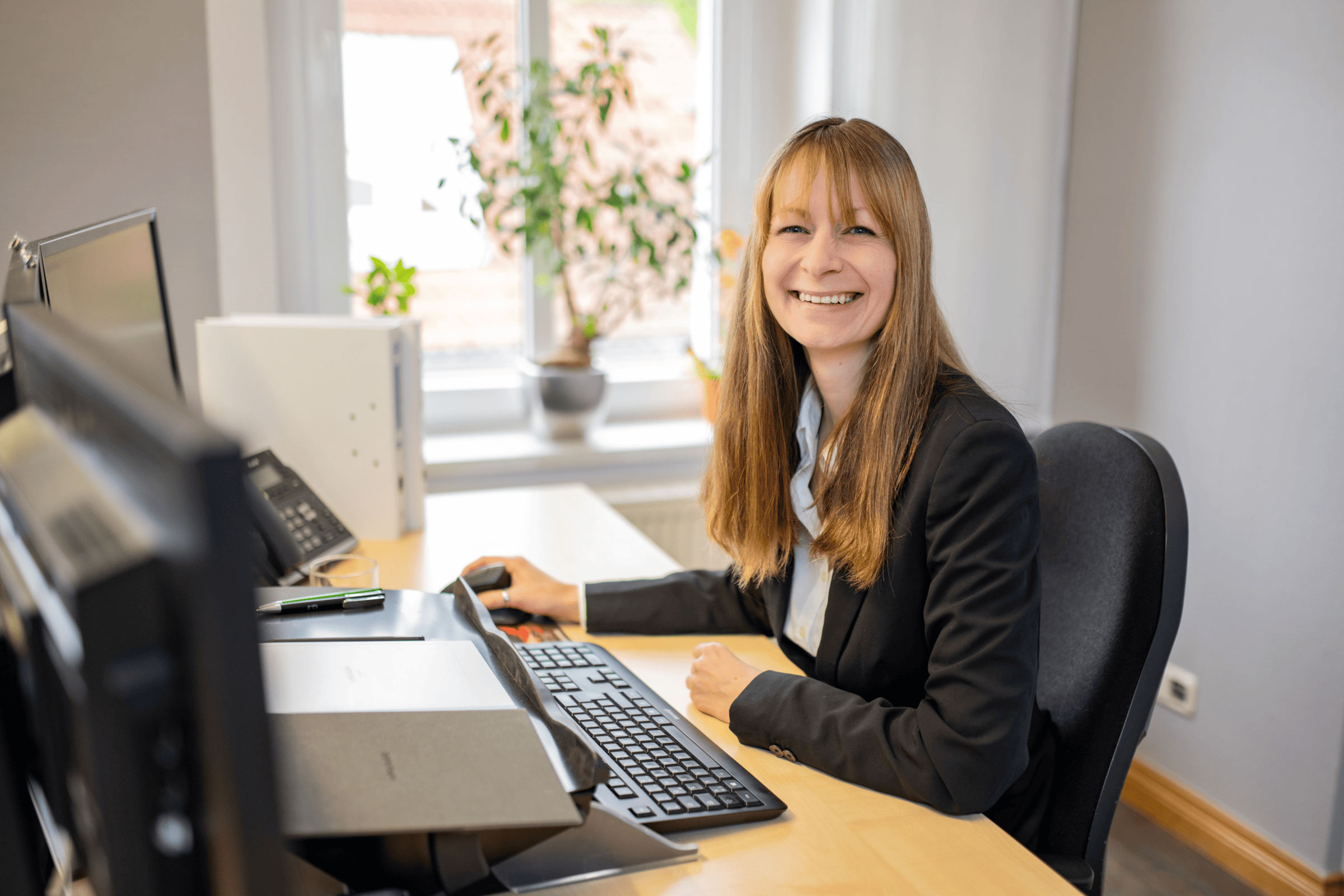 Frau am Arbeitsplatz bei ETL Englert & Collegen, die herzlich in die Kamera lacht