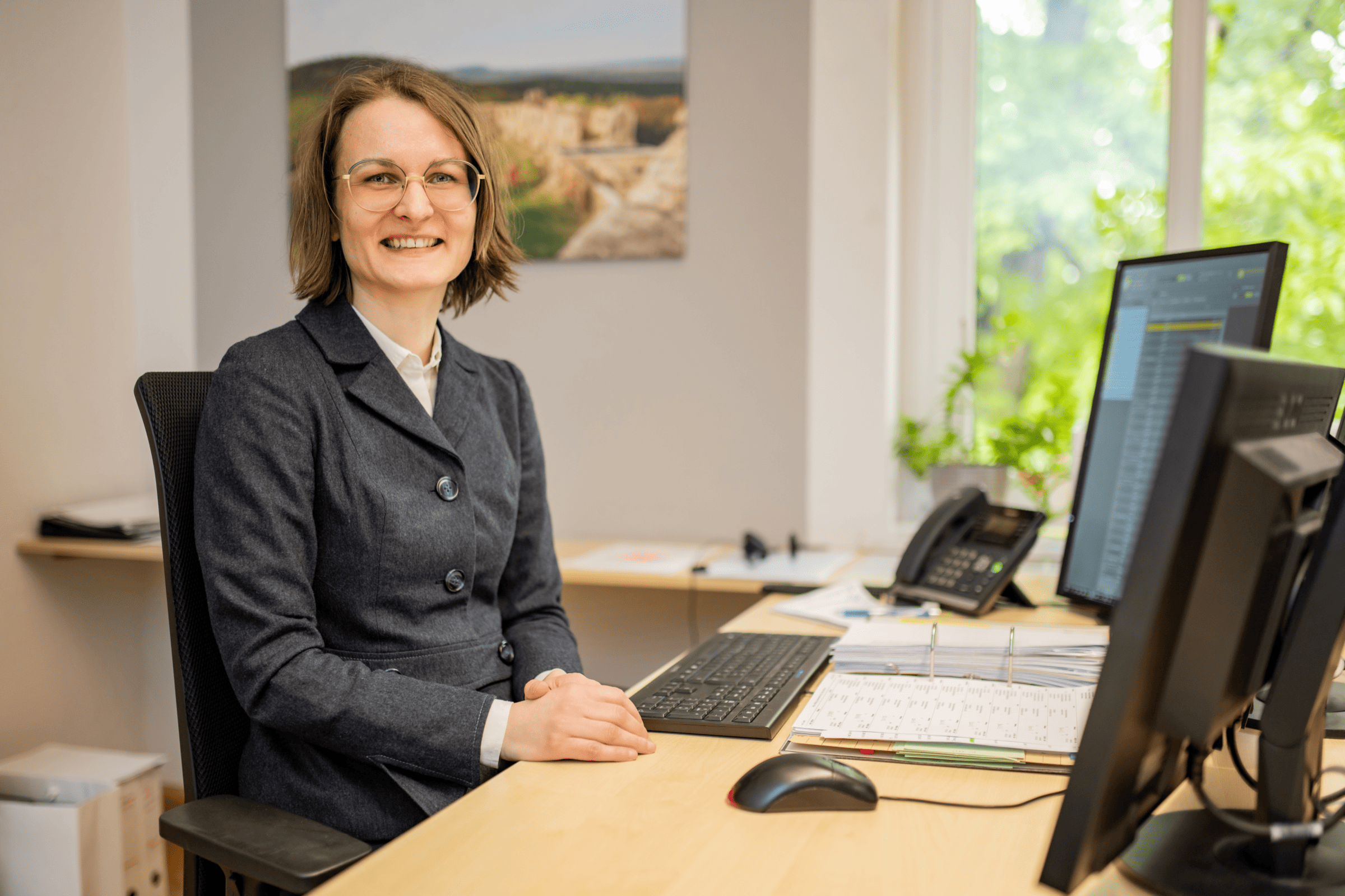 Frau am Arbeitsplatz bei ETL Englert & Collegen, die freundlich in die Kamera schaut