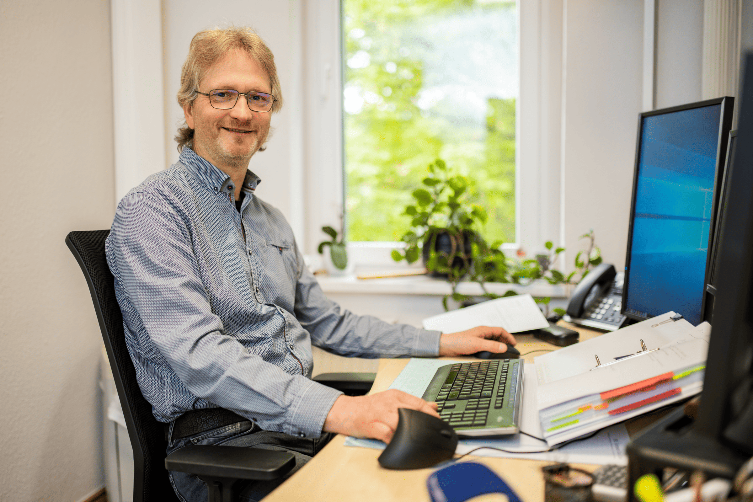 Mann am Arbeitsplatz bei ETL Englert & Collegen, der freundlich in die Kamera schaut